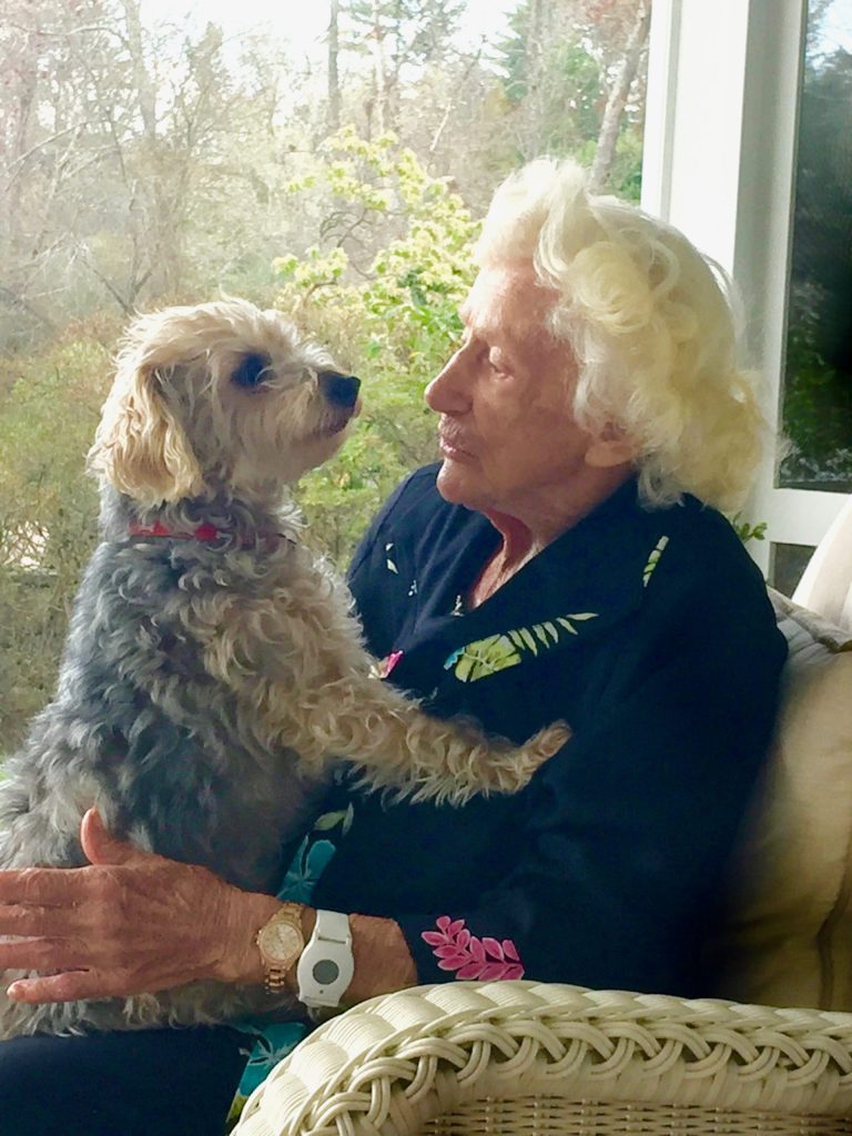 Elderly woman lovingly holds her small dog.